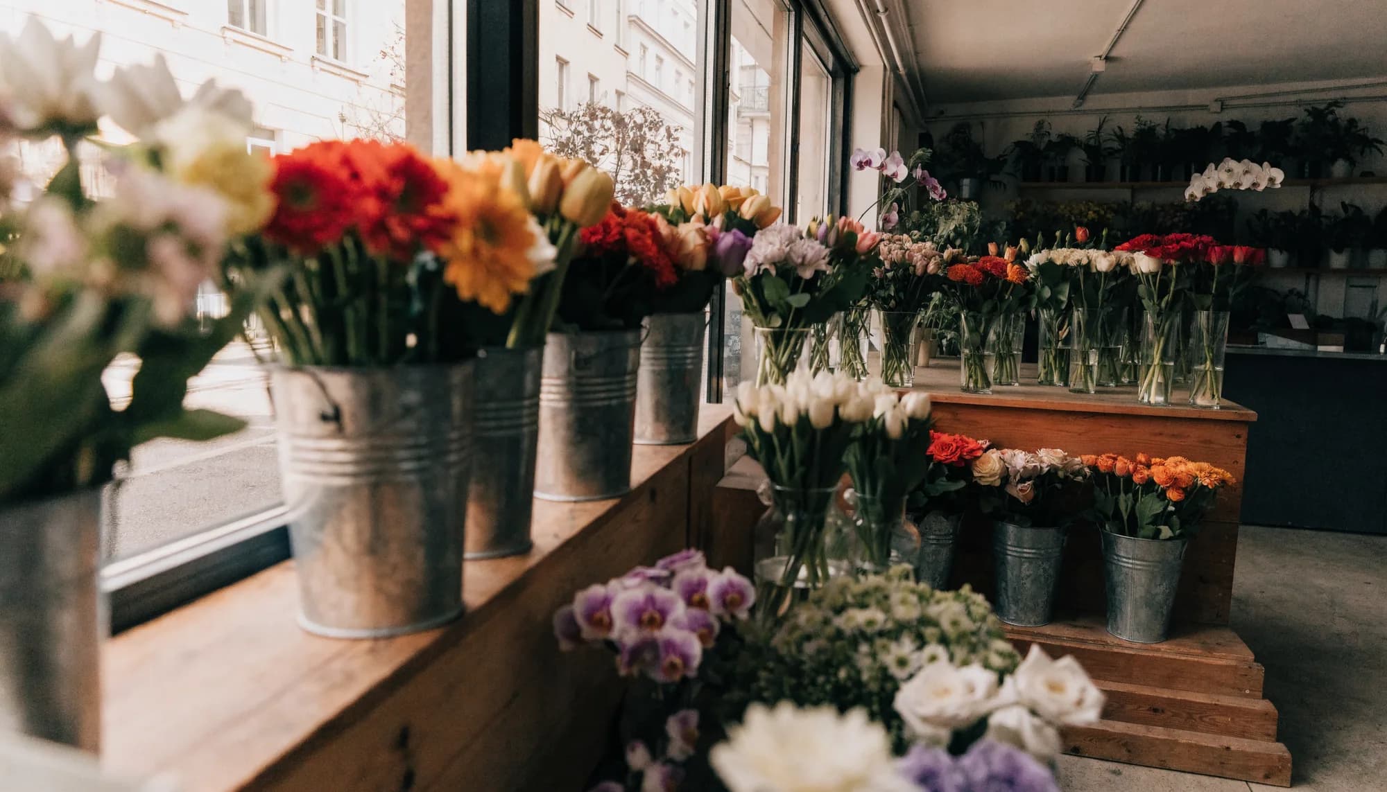 Blumenladen mit Eimern voller frischer Schnittblumen am Schaufenster