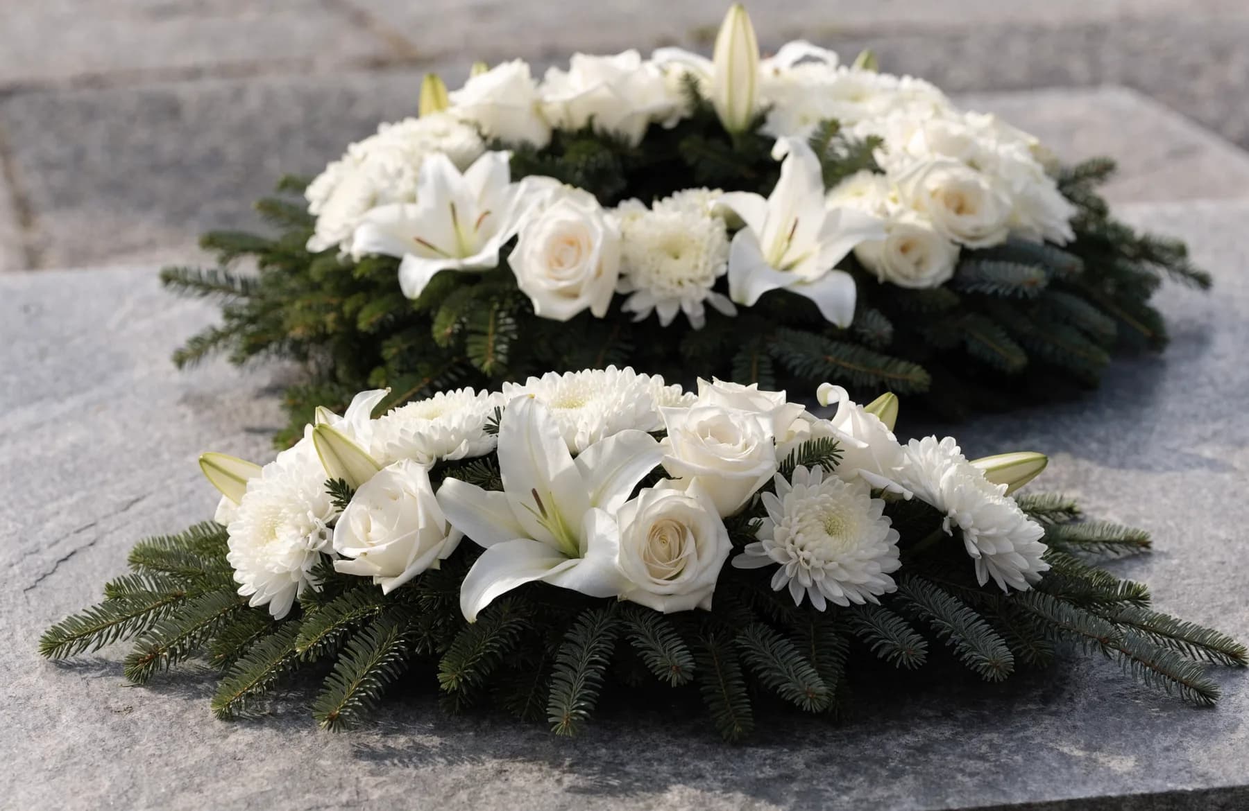 Trauerkranz und Bodengesteck aus weißen Lilien, Rosen und Tannengrün