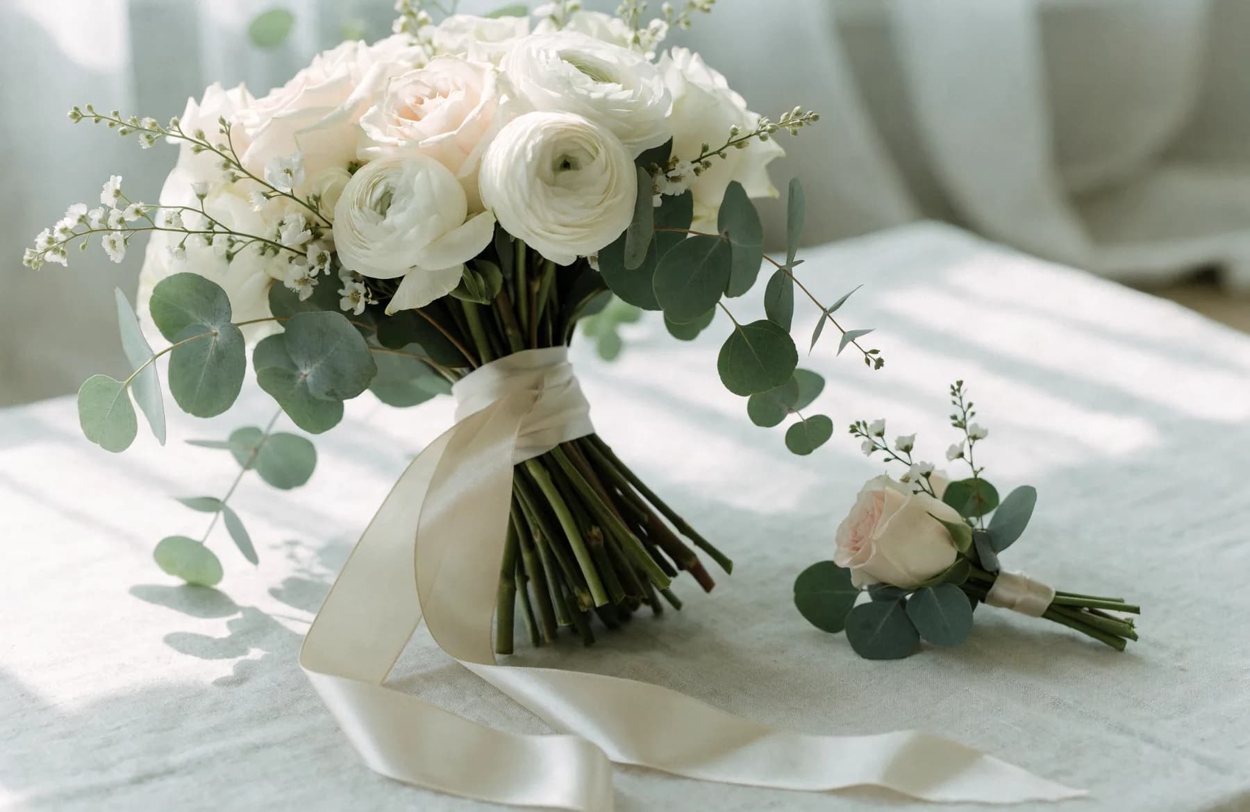 Brautstrauß aus weißen Rosen und Ranunkeln mit passendem Anstecker